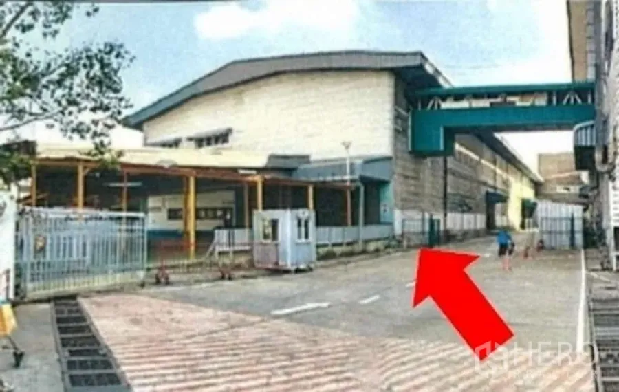 Warehouse for rent in Phra Pradaeng, Samut Prakan - Gated warehouse entrance with guard booth and wide driveway for trucks.