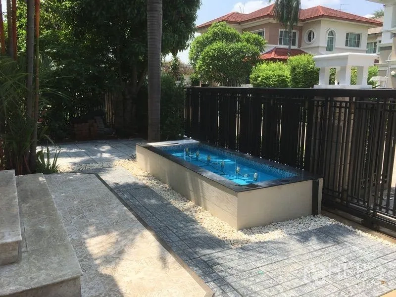 บ้าน ให้เช่า - ลานหน้าบ้านจัดสวนพร้อมบ่อน้ำพุทรงสี่เหลี่ยม ข้างรั้วเหล็กสีดำและทางเดินปูกระเบื้อง ใต้ร่มไม้ใหญ่