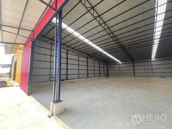 Warehouse for rent in Ban Pho, Chachoengsao - Clear-span warehouse interior showing skylight strips, steel trusses, and smooth concrete floor.