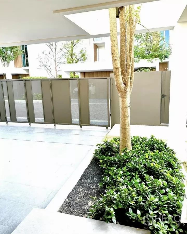 Detached House for rent in Saphan Sung, Bangkok - Covered carport with planter bed, tree and privacy sliding gate at the entrance.