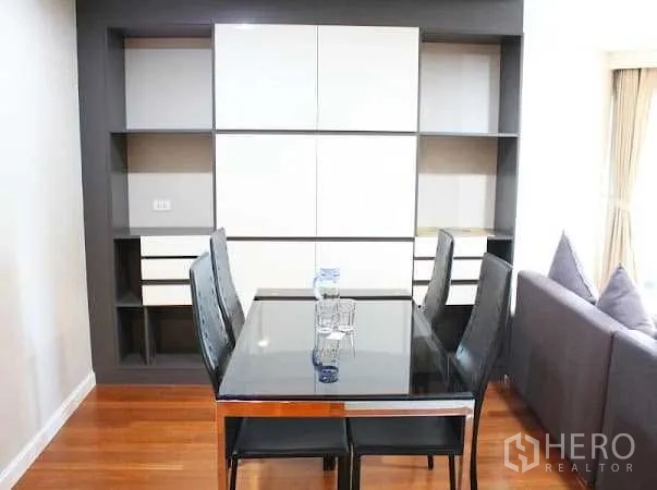 Condominium for rent in Huai Khwang, Bangkok - Four-seat dining table with black chairs set against a feature storage wall.