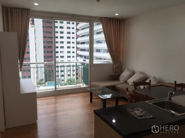 คอนโด ให้เช่าหรือขายในWatthana, Bangkok - พื้นที่นั่งเล่นเปิดสู่ระเบียง โซฟาเข้ามุม และวิวเมืองข้างครัวเปิด
