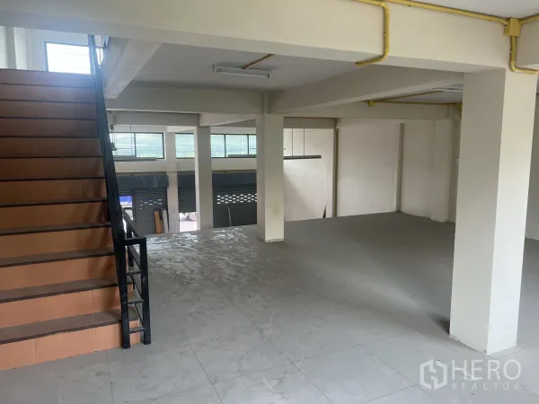 Home Office for rent in Suan Luang, Bangkok - Mezzanine-style workspace with internal staircase, support columns and wide windows overlooking the street.