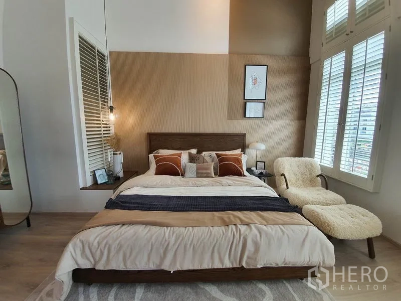 Detached House for rent in Prawet, Bangkok - Master bedroom with tall shuttered windows, upholstered chaise and warm tones.