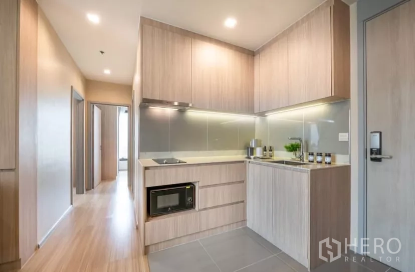 คอนโด ให้เช่าในChatuchak, Bangkok - ครัวรูปตัวแอล เตาไฟฟ้าพร้อมฮูด ไมโครเวฟ ตู้เก็บของจำนวนมาก และพื้นกระเบื้องสีเทา.