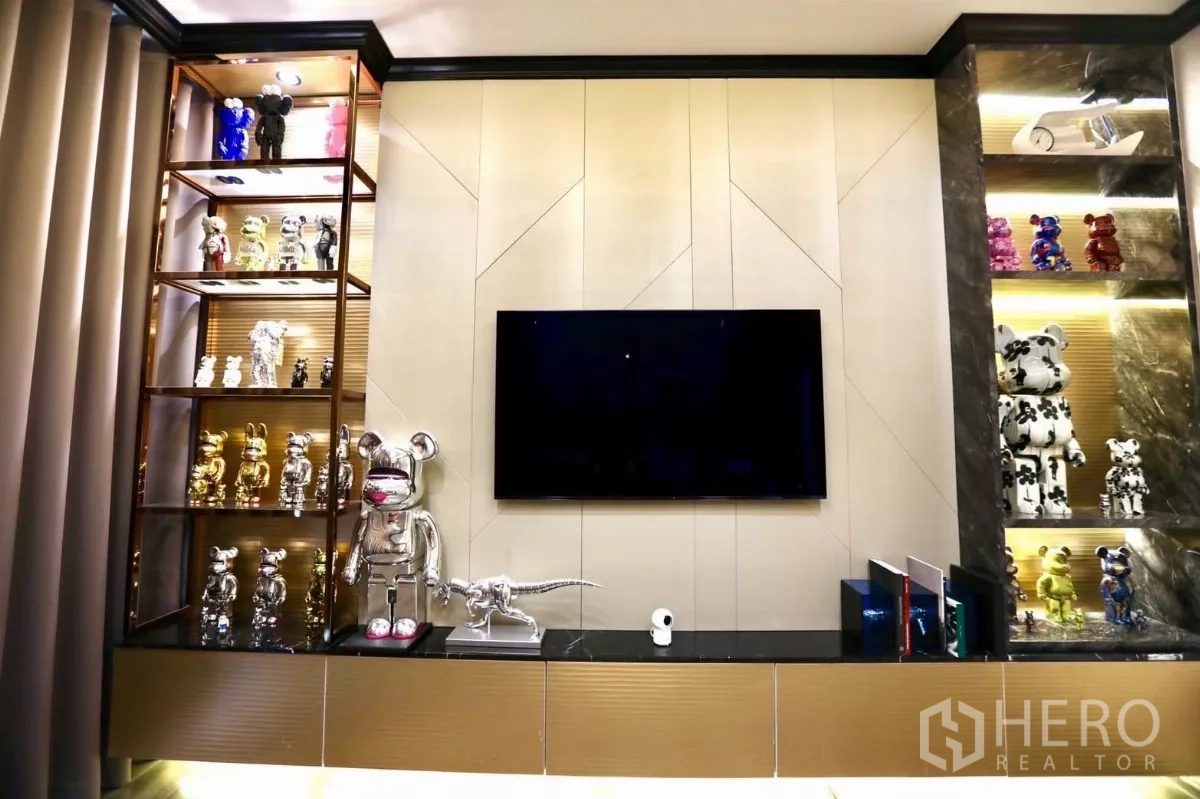 Detached House for rent in Samut Prakan - Bedroom media wall with TV, lit display shelves and warm wood flooring.