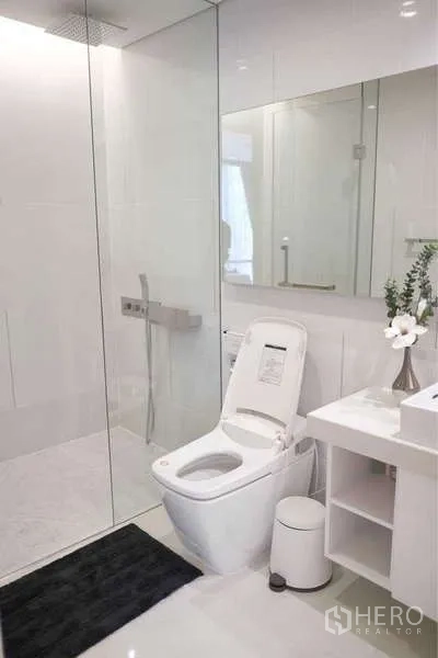 Condominium for rent in Sathon, Bangkok - Contemporary white bathroom with glass-enclosed rain shower and smart toilet.