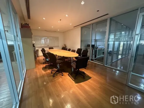 Office Space for rent - Glass-walled conference room with oval table and swivel chairs on wooden flooring