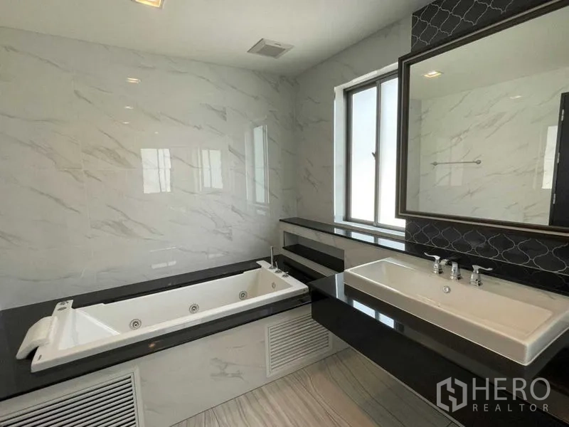 บ้าน ให้เช่าหรือขายในLat Krabang, Bangkok - ห้องน้ำพร้อมอ่างอาบน้ำจากุซซี่ข้างหน้าต่าง และอ่างล้างหน้าใบใหญ่บนท็อปสีดำ