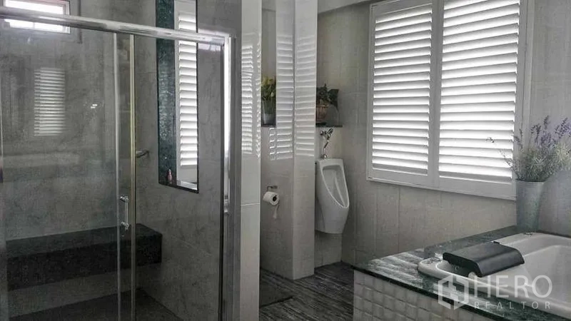 Home Office for sale in Phasi Charoen, Bangkok - Second bathroom with shower enclosure, urinal, louvered windows and a stone-top vanity.