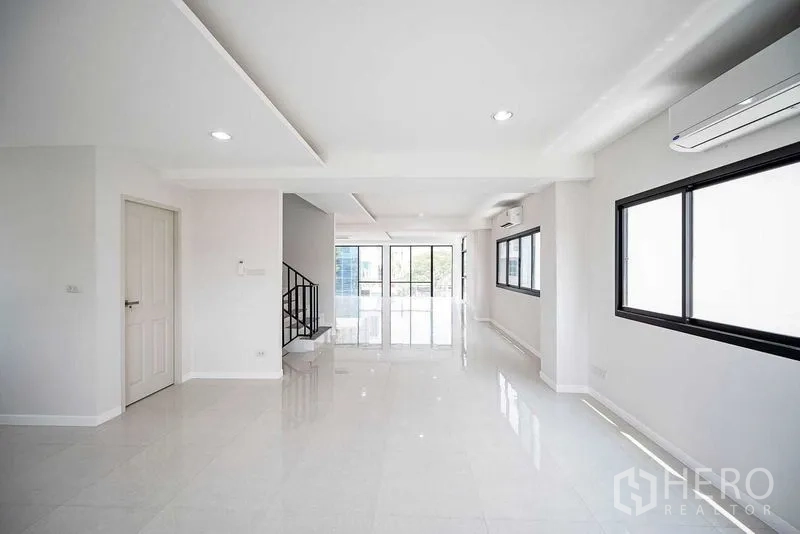 Home Office for rent in Suan Luang, Bangkok - Bright open-plan office level with white tile floors, balcony doors, and a side staircase.