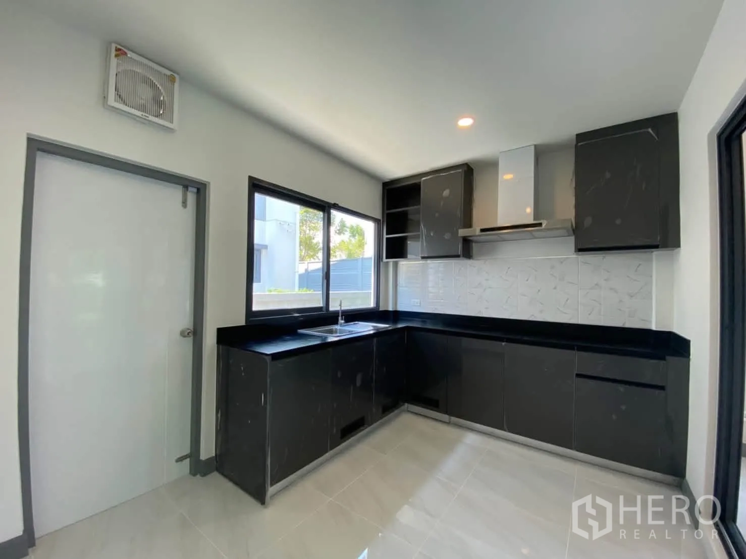 บ้านเดี่ยว for rent or sale in Prawet, Bangkok - ครัวรูปตัวแอลสไตล์โมเดิร์น ตู้สีดำ เคาน์เตอร์หิน หน้าต่าง และเครื่องดูดควัน