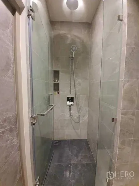 Condominium for rent - Stone-tiled shower room with glass doors and handheld shower.