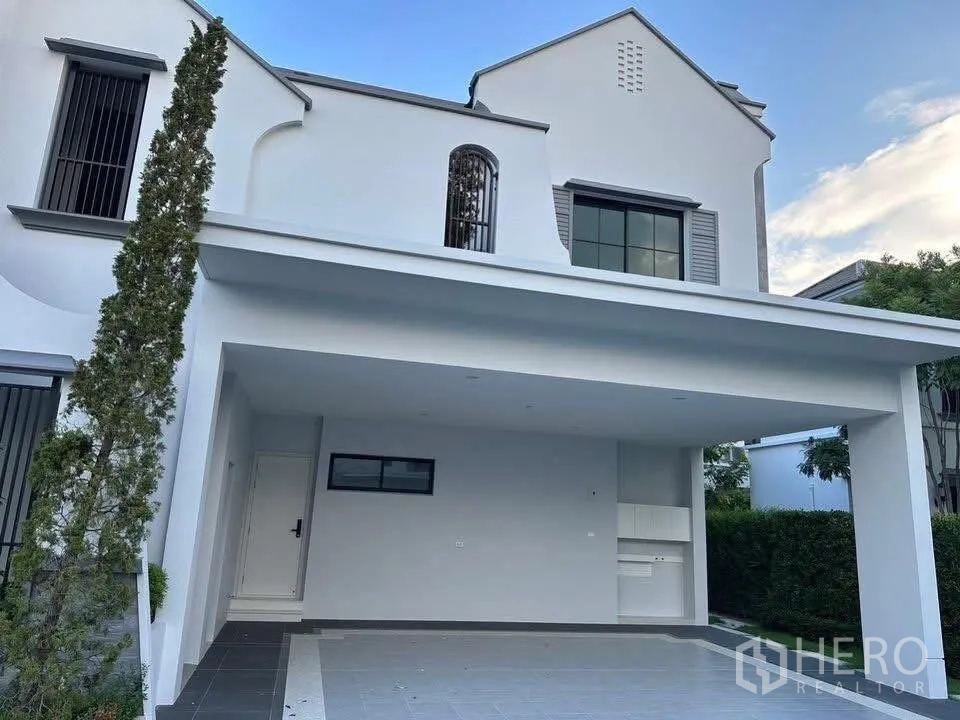 Detached House for sale in Taling Chan, Bangkok - Covered carport and driveway of the modern white house with space for multiple cars.