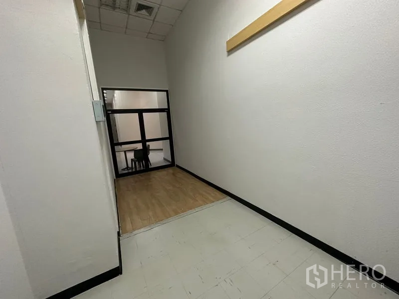 สำนักงาน ให้เช่า - โถงภายในอาคารพร้อมพื้นยกระดับเล็กน้อย หน้าต่างกรอบดำ และผนังโทนเรียบ