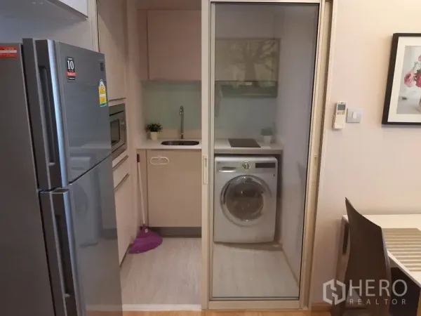 คอนโด ให้เช่าในWatthana, Bangkok - ครัวขนาดกะทัดรัดพร้อมประตูกระจกบานเลื่อน เตา ซิงก์ และเครื่องซักผ้าฝาหน้าในคอนโด