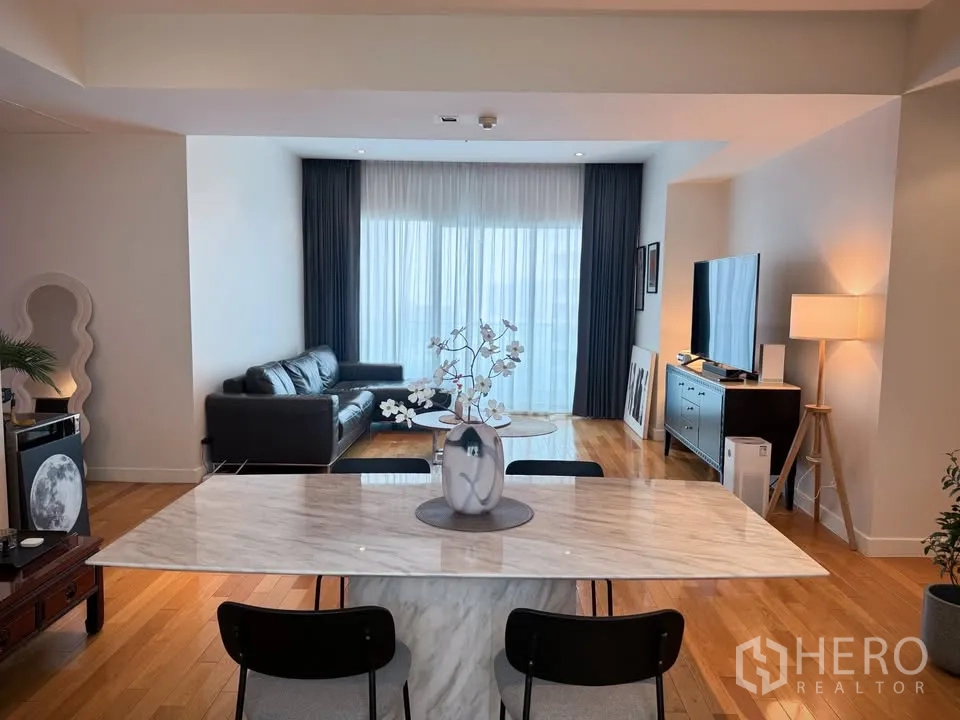 คอนโด for rent or sale in Khlong Toei, Bangkok - มุมทานอาหารโต๊ะหินอ่อนเชื่อมต่อห้องนั่งเล่น โซฟาหนังและผ้าม่านโปร่ง
