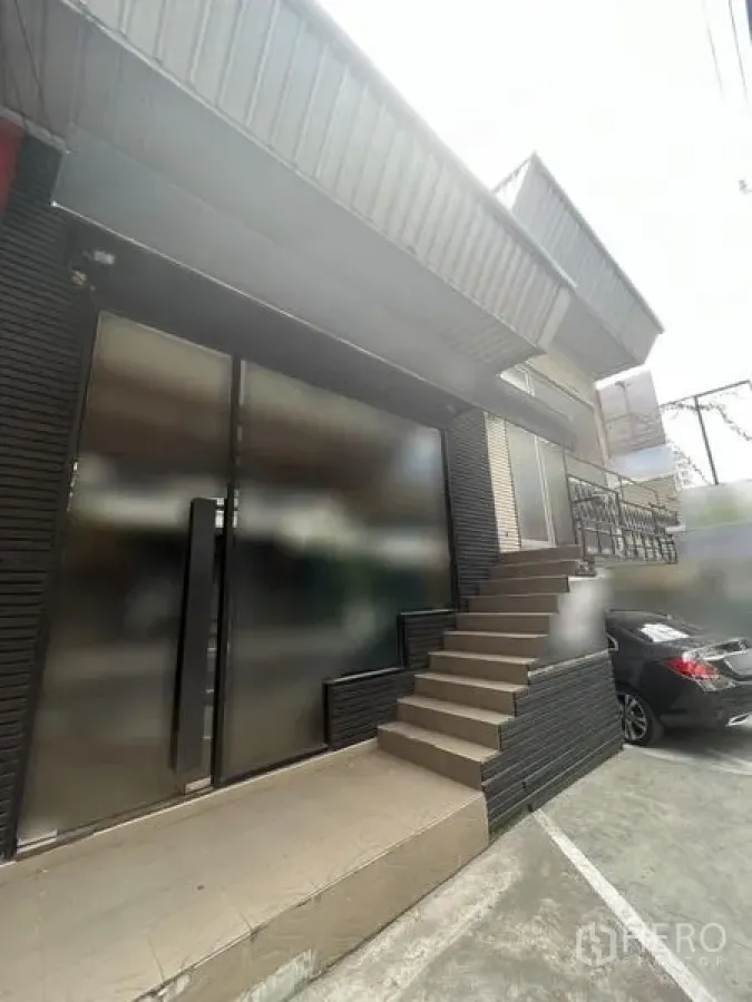 零售空间 出租在Watthana, Bangkok - 临街商铺外观，宽幅玻璃门、侧边台阶及门前停车位。