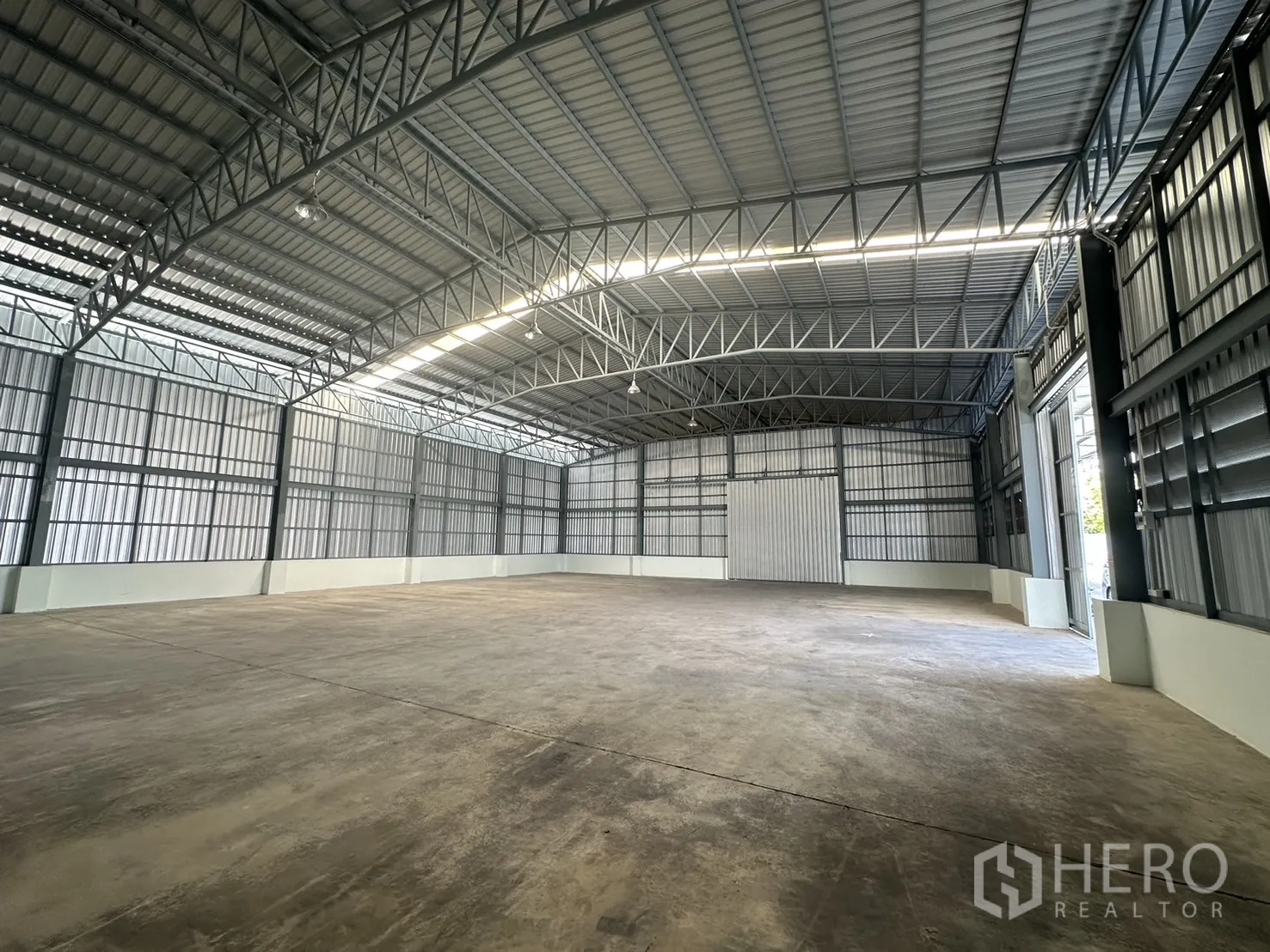 Warehouse for rent in Mueang Pathum Thani, Pathum Thani - Bright warehouse interior with steel columns, ventilated side panels and polished concrete surface.