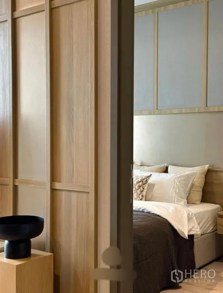 公寓 出租或出售在Watthana, Bangkok - 滑门旁可见卧室一角，木质墙面与铺好的床品。