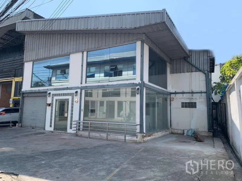 Warehouse for rent in Suan Luang, Bangkok - Angled view of a two-storey warehouse with showroom windows and front parking apron.