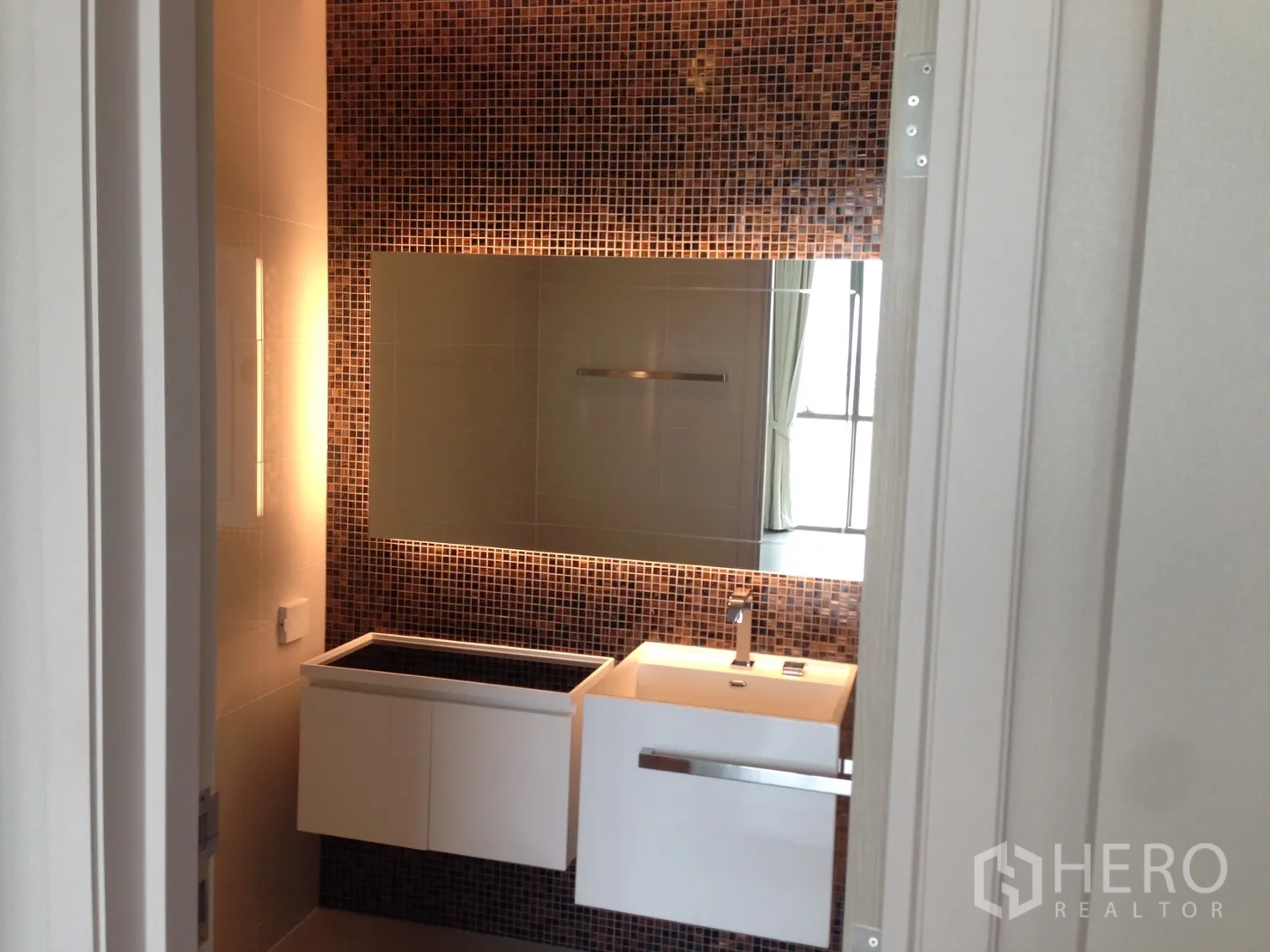 Condominium for rent in Bang Sue, Bangkok - Bathroom with mosaic feature wall, large backlit mirror and floating vanity.