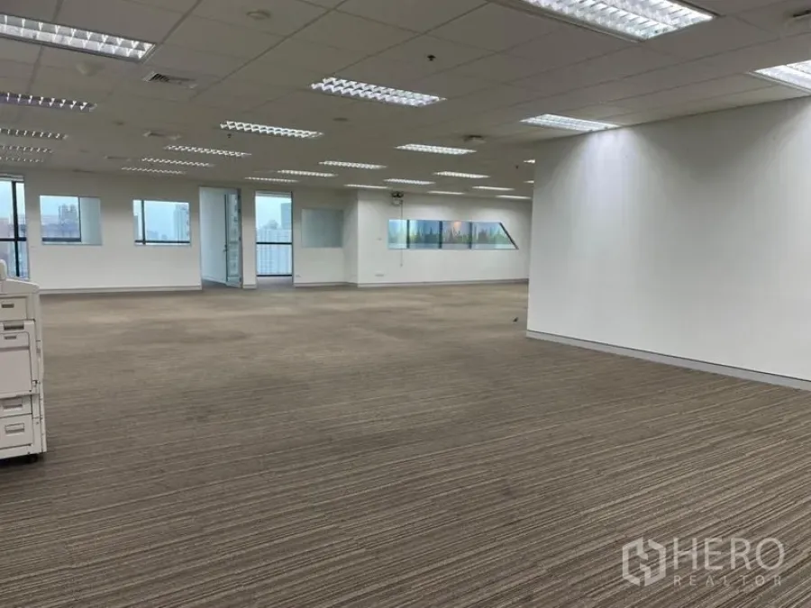 Office Space for rent - Wide office area with carpet flooring, multiple light panels and rooms divided by glass.