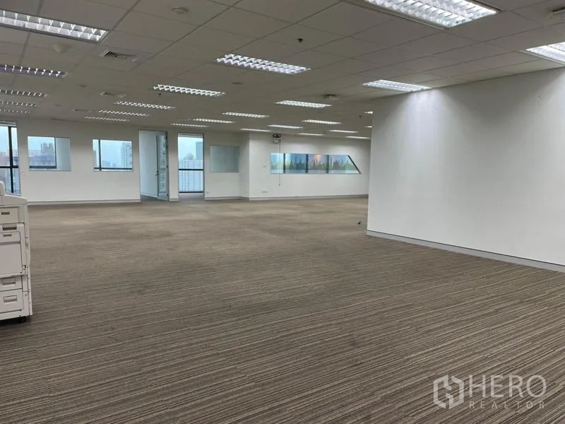 Office Space for rent - Wide office area with carpet flooring, multiple light panels and rooms divided by glass.