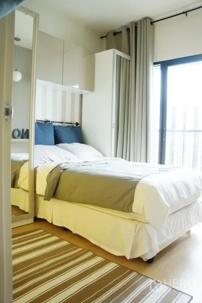 คอนโด ให้เช่าในPhaya Thai, Bangkok - ห้องนอนสว่าง เตียงสีขาว ตู้เสื้อผ้าบานกระจก พรมลายทาง และประตูกระจกออกระเบียง