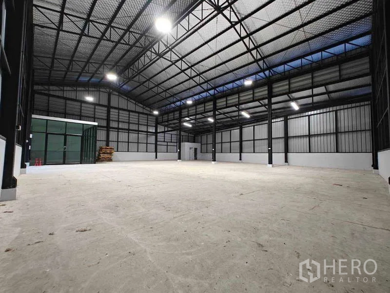 Warehouse for rent in Sam Phran, Nakhon Pathom - Spacious warehouse interior with high steel truss roof, skylight panels, LED lighting and concrete floor.