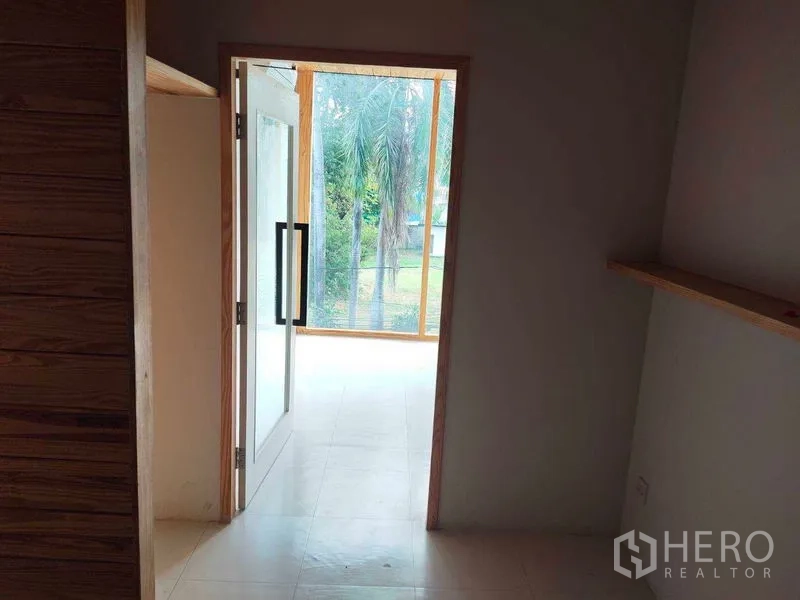 办公空间 出租在Khlong Toei, Bangkok - 室内走廊，玻璃门通向采光充足的会谈区，花园景观与壁挂搁板。