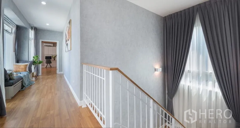 Detached House for sale in Lam Luk Ka, Pathum Thani - Upstairs landing with long bench window seat, grey curtains and wood flooring.