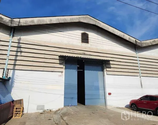 Warehouse for rent in Khlong Toei, Bangkok - Street-level view of the warehouse facade with gable roof and oversized blue entry doors.