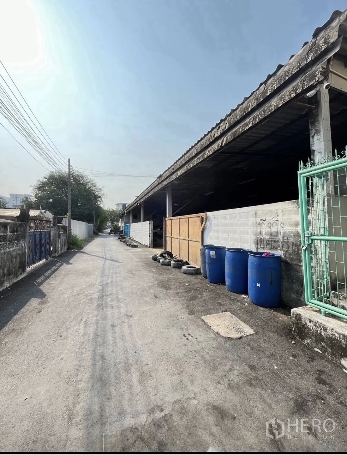 仓库 for rent in Chatuchak, Bangkok - 仓库外侧沿巷道一侧，墙边摆放有桶和轮胎。