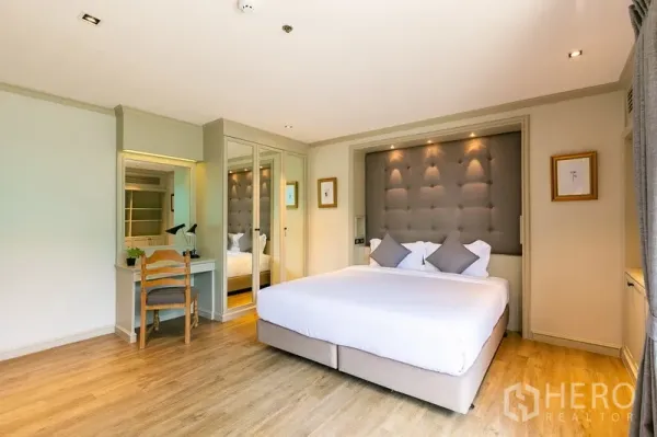 อพาร์ทเมนท์ ให้เช่าในKhlong Toei, Bangkok - ห้องนอนหลักหัวเตียงบุผ้า ตู้เสื้อผ้าบานกระจก และโต๊ะเครื่องแป้งขนาดกะทัดรัด