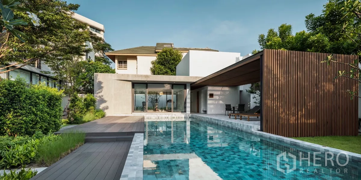 Condominium for rent in Bang Kapi, Bangkok - Outdoor swimming pool with wooden sun deck, shaded pavilion and lush greenery.