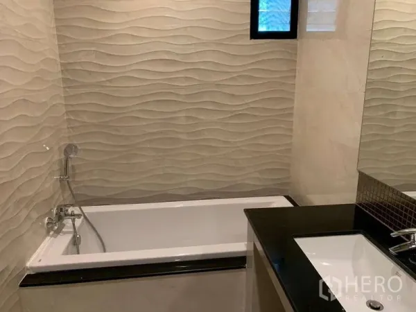 Detached House for rent - Bathroom with wave-pattern wall tiles, built-in bathtub and black stone countertop sink.
