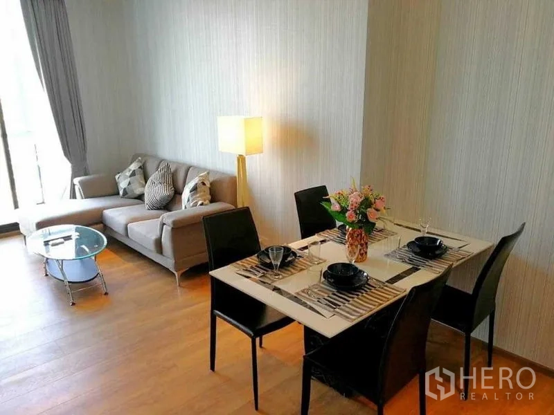คอนโด ให้เช่า - ห้องนั่งเล่นอบอุ่น โซฟาเข้ามุม โคมไฟตั้งพื้น และชุดรับประทานอาหารข้างหน้าต่างบานใหญ่