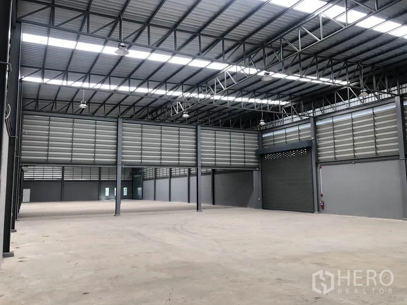 工厂 出租或出售在Bang Bo, Samut Prakan - 仓库内部，配卷帘装卸门与钢桁架屋顶。