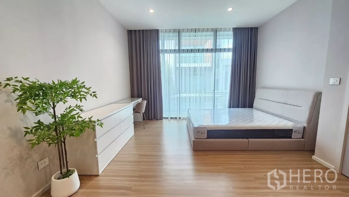 ทาวน์เฮาส์ ให้เช่าในSaphan Sung, Bangkok - ห้องนอนใหญ่สว่าง มีเตียง ตู้ลิ้นชักยาว โต๊ะทำงาน และประตูกระจกสู่ระเบียง