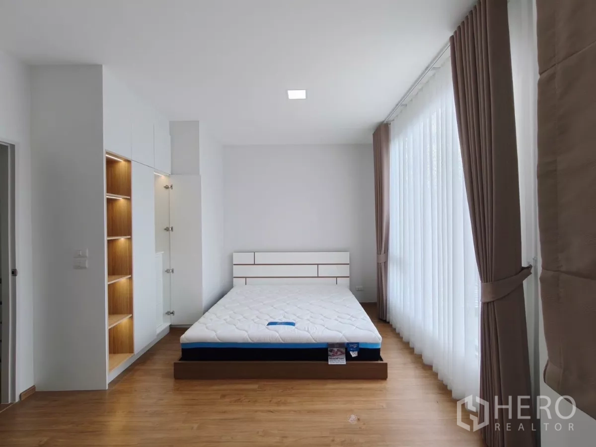 Townhouse for rent in Bang Phli, Samut Prakan - Spacious master bedroom with floor-to-ceiling windows, sheer curtains, built-in wardrobe and bed.