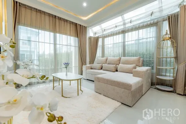 บ้าน ให้เช่าหรือขายในBang Khen, Bangkok - มุมนั่งเล่นรับแสงธรรมชาติ โซฟา L-Shape กระจกโค้งรอบด้าน โต๊ะกลางทรงกลม และพรมฟู