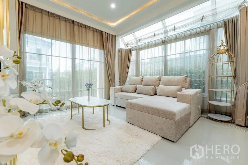 บ้าน ให้เช่าหรือขายในBang Khen, Bangkok - มุมนั่งเล่นรับแสงธรรมชาติ โซฟา L-Shape กระจกโค้งรอบด้าน โต๊ะกลางทรงกลม และพรมฟู