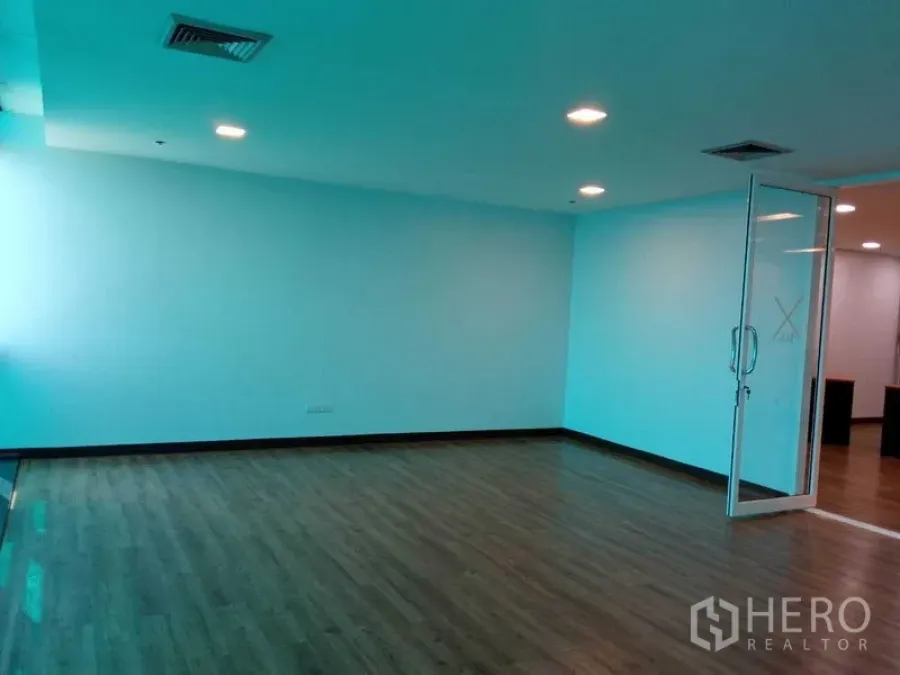 Office Space for rent in Din Daeng, Bangkok - Open-plan office with recessed lighting, wood floors, and a glass door entry to meeting area.