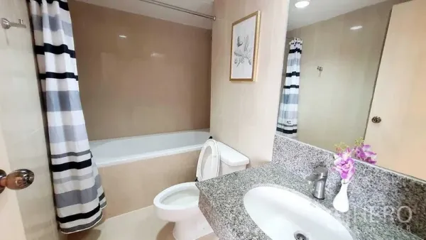 Condominium for sale in Bang Kho Laem, Bangkok - Bathroom with bathtub, striped shower curtain, granite vanity and large mirror.