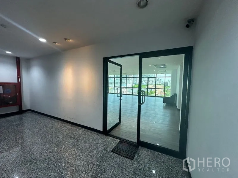 办公空间 出租在Khlong Toei, Bangkok - 玻璃入口门通向采光充足的开放式办公区，窗外城市景观