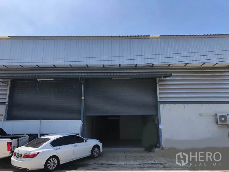 คลังสินค้า ให้เช่าในMueang Samut Prakan, Samut Prakan - ด้านหน้าโกดังอุตสาหกรรม ประตูม้วนโลหะขนาดใหญ่ พร้อมพื้นที่จอดรถ