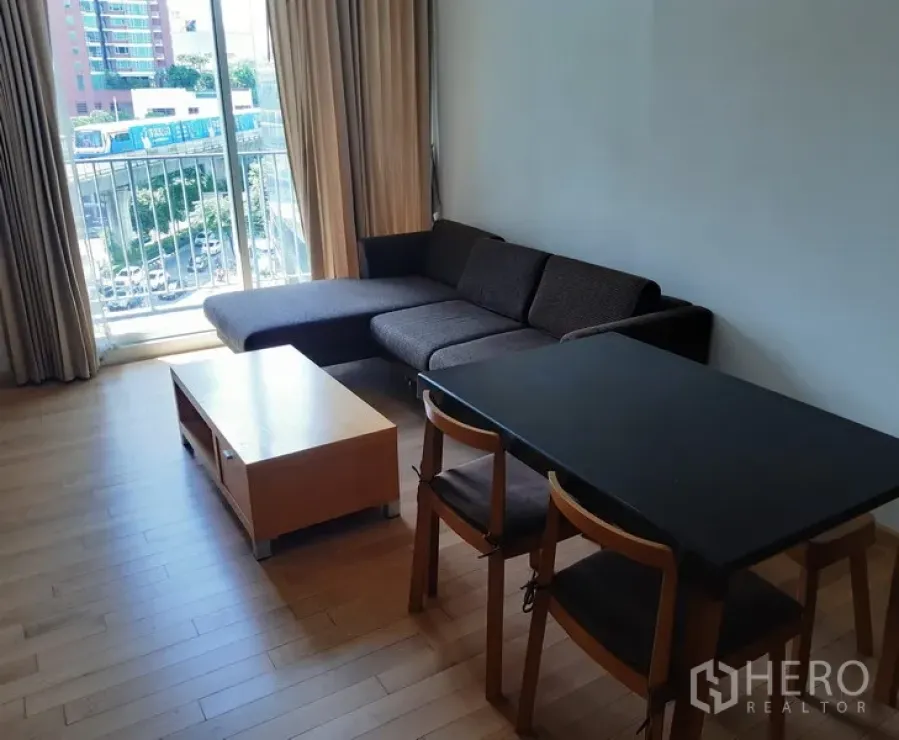 คอนโด ให้เช่าในKhlong Toei, Bangkok - ห้องนั่งเล่นรับประทานอาหาร พื้นไม้ โซฟาเข้ามุม ประตูบานเลื่อนออกสู่ระเบียงวิวเมือง