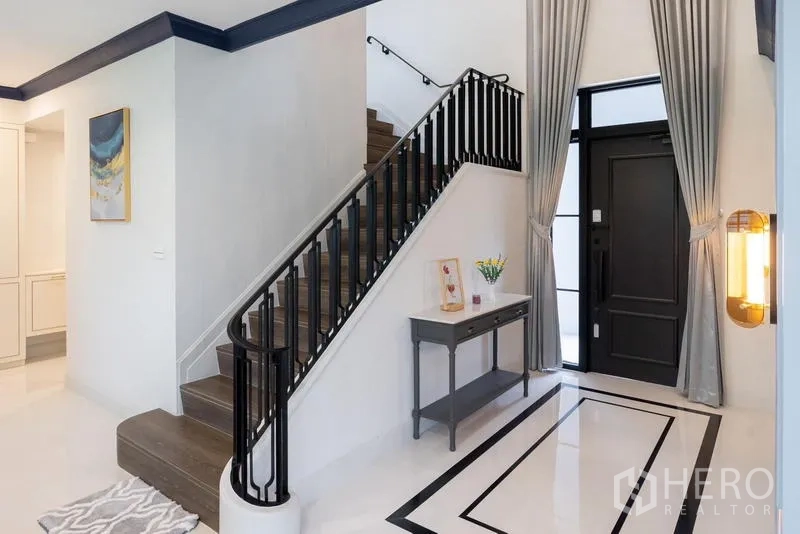 Detached House for sale in Saphan Sung, Bangkok - Elegant foyer with black front door and staircase with dark metal balustrade.