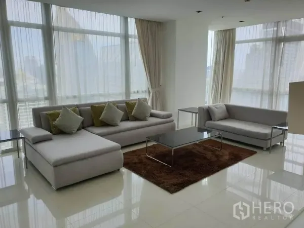 公寓 出租在Pathum Wan, Bangkok - 采光充足的客厅，落地窗、灰色沙发与曼谷天际线景观。